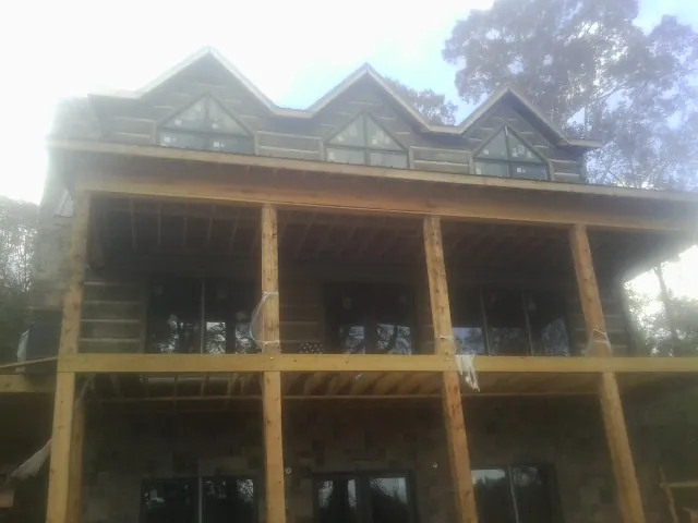 Dormers and porch framing on a large log home under construction — Roof Coating work by our crew in Sioux City