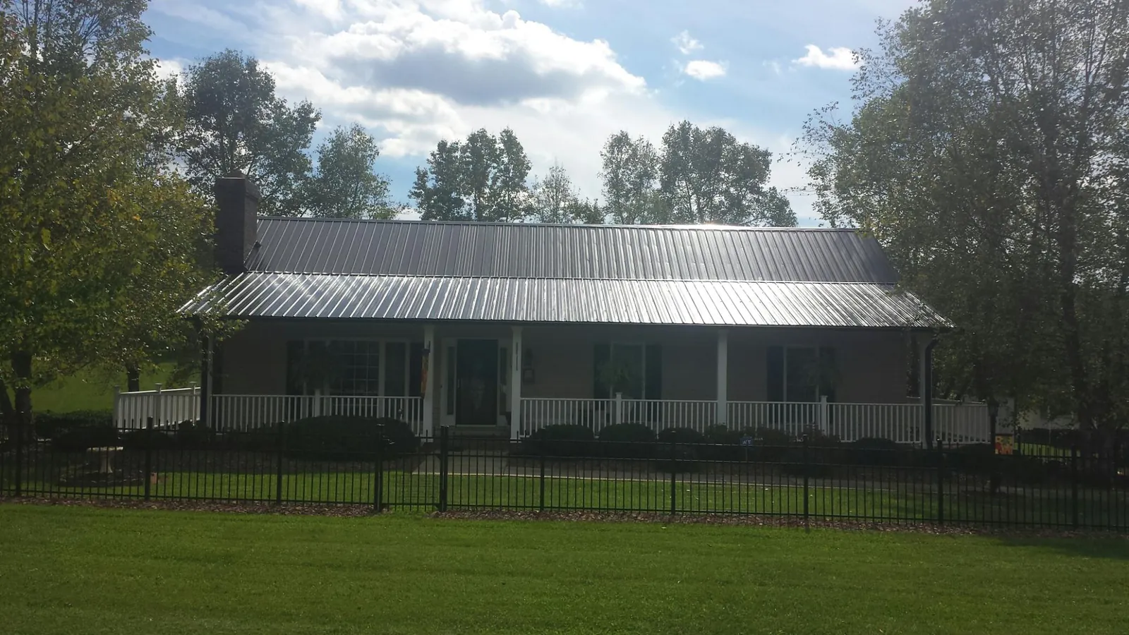 Gray metal roof on a brick ranch with a full width front porch — Gutter Guard Installation work by our crew in Sioux City