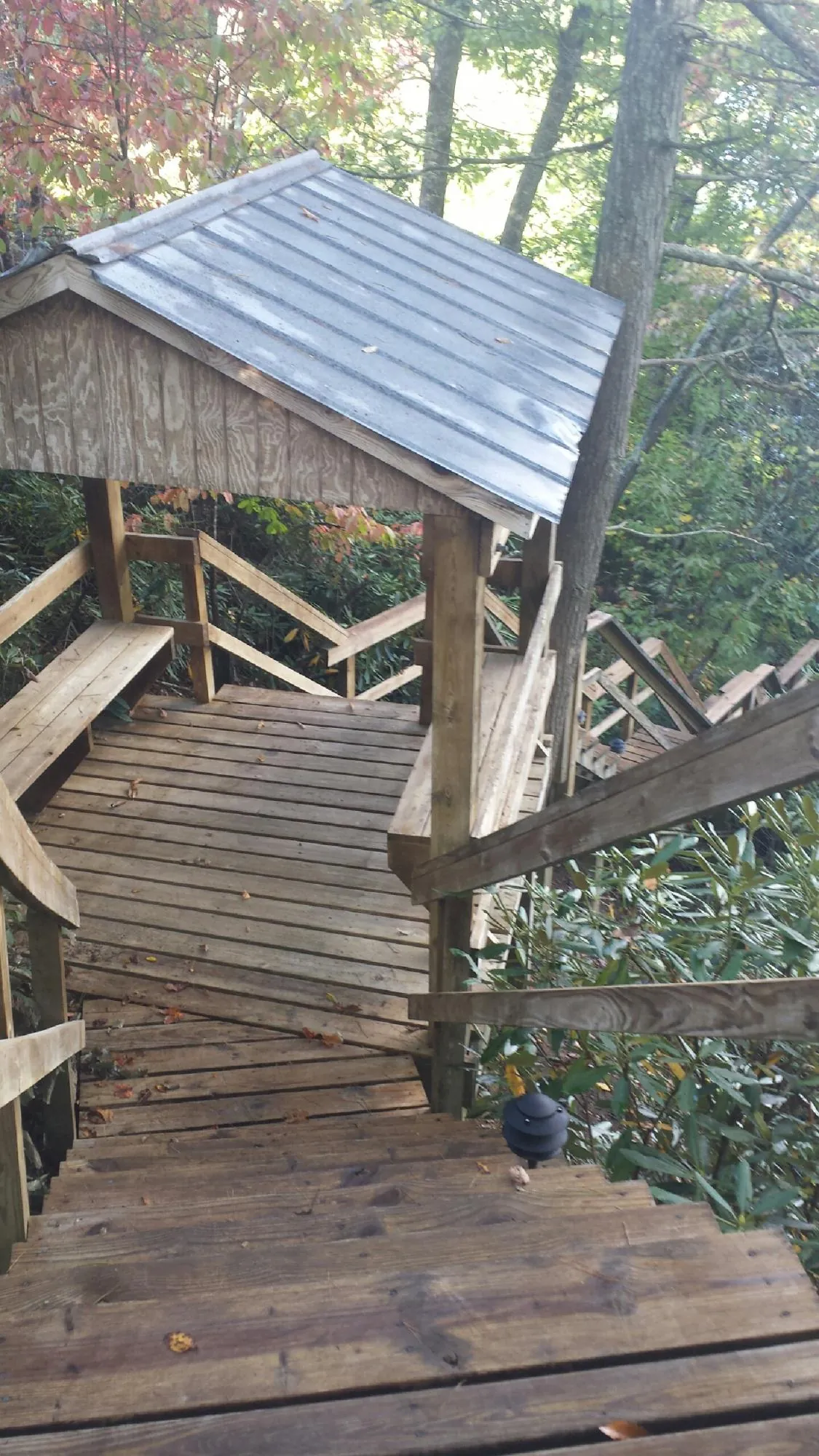 Metal roofed shelter over wooden steps on a wooded walkway — Skylight Repair & Installation work by our crew in Sioux City