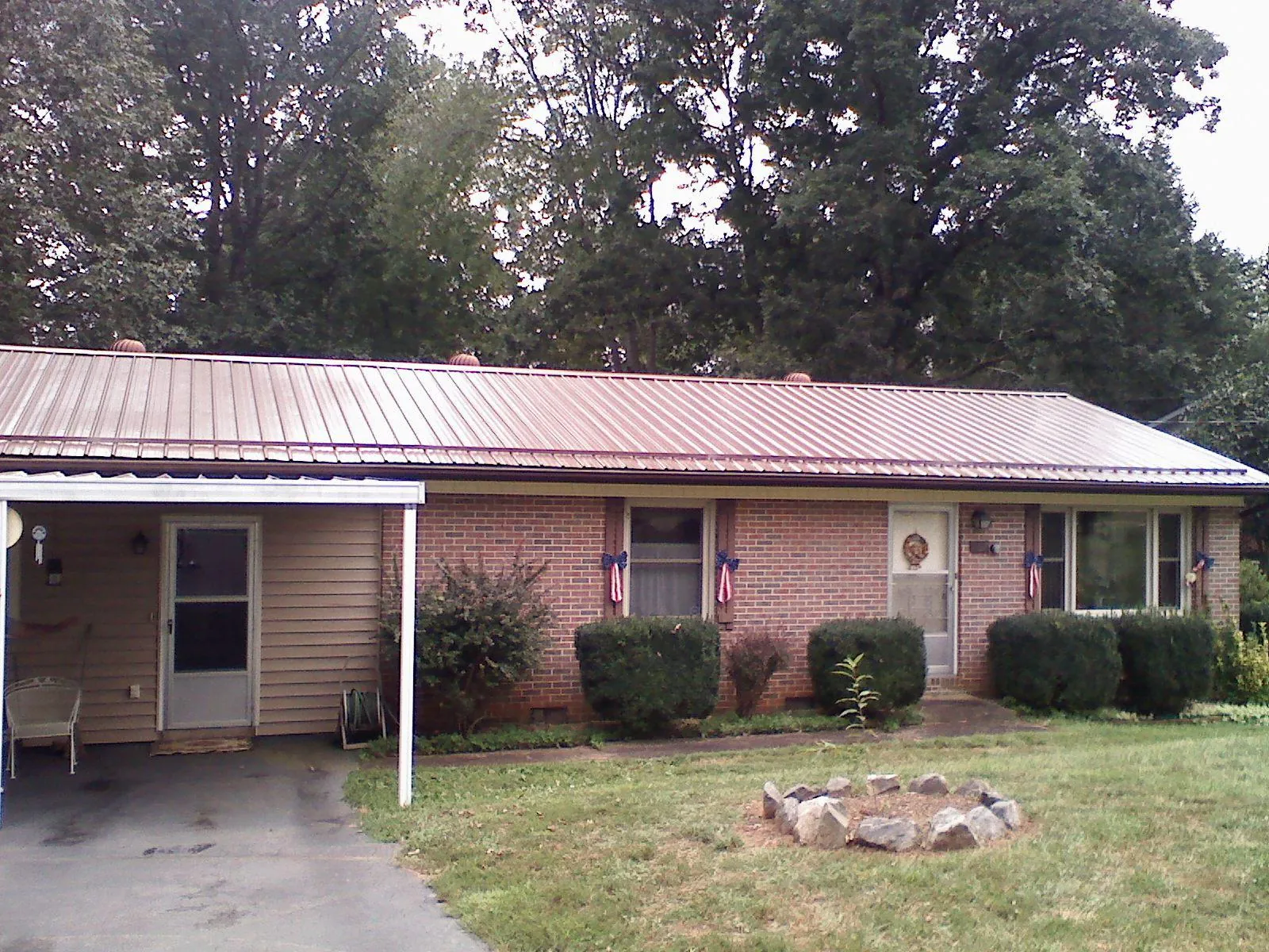 Bronze metal roof and carport on a brick ranch home — Roof Repair work by our crew in Sioux City