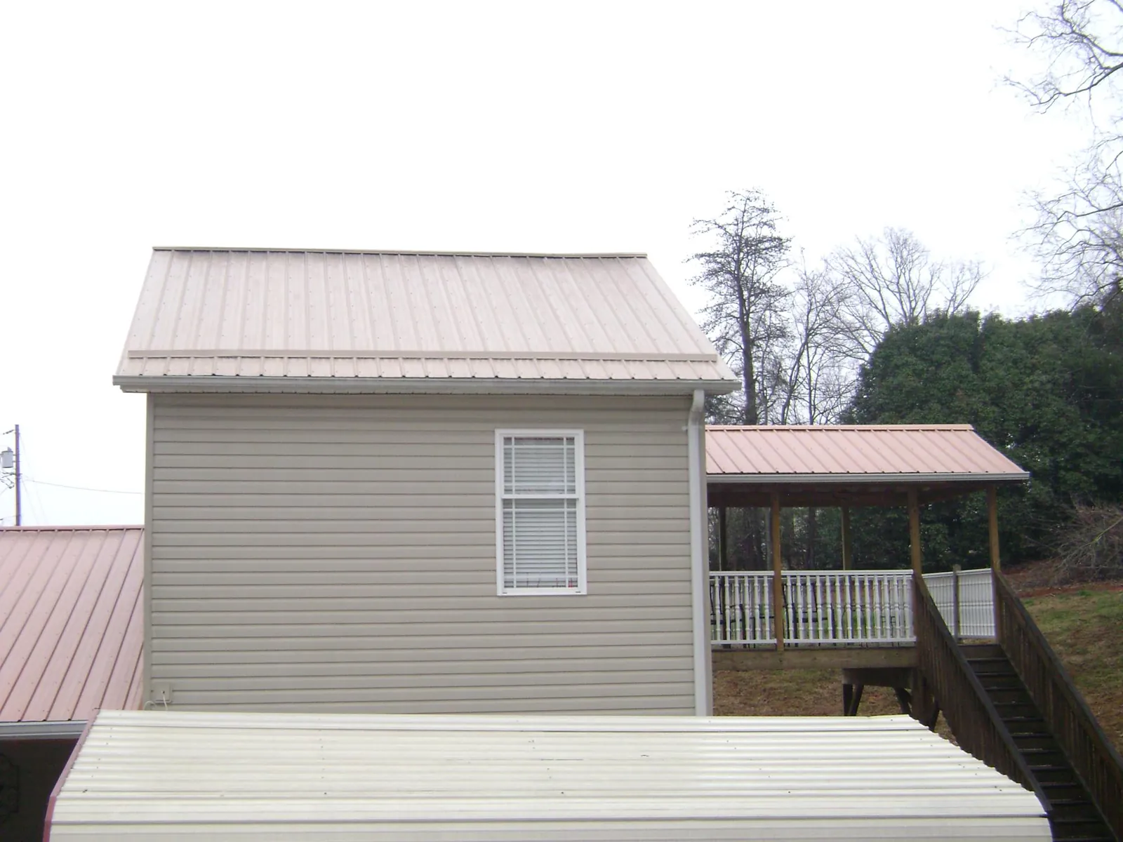 Tan metal roofs on a two story addition and attached porch, from a Roof Replacement job in Sioux City