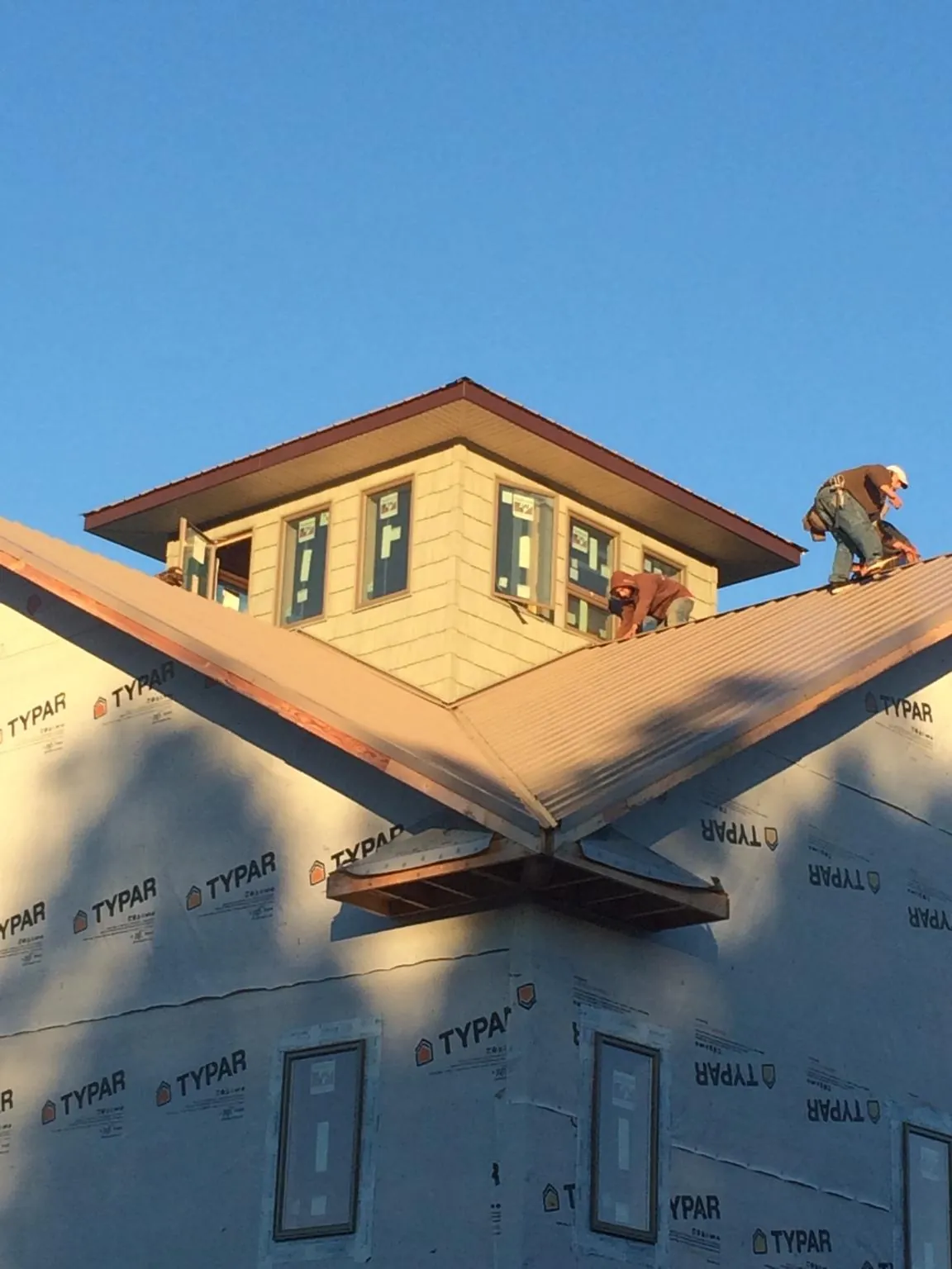 Roofers working around a rooftop cupola on a new metal roof at sunset — Roof Waterproofing in Sioux City by Roofing Brothers